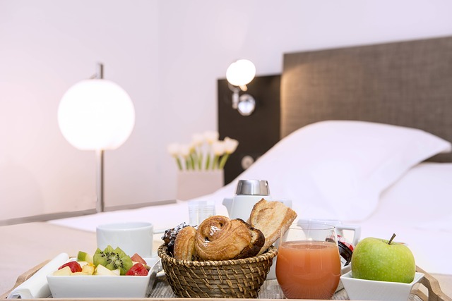 snídaně v posteli, jablko, džus, pečivo, ovoce v miskách a za tím postel a polštář